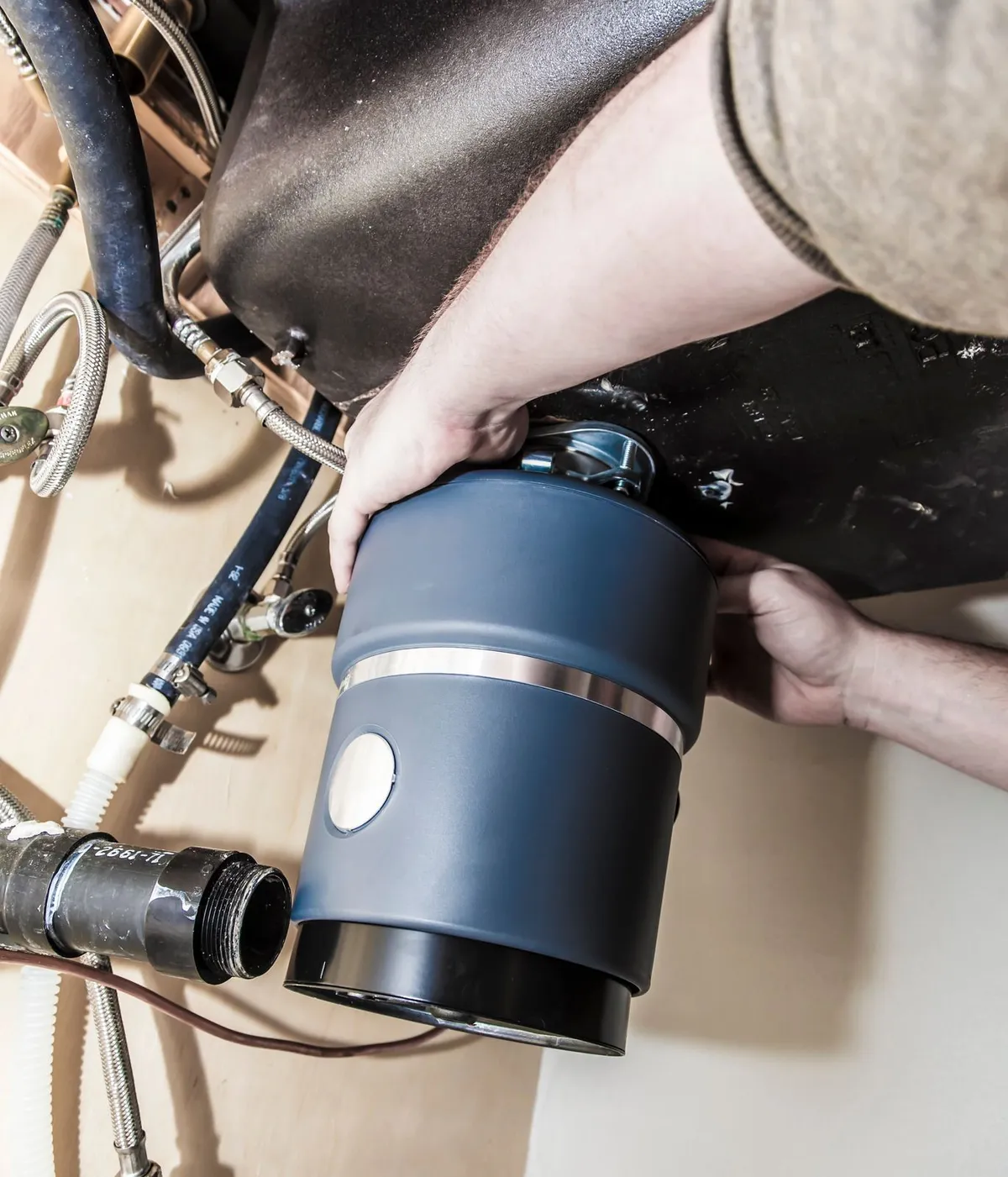 A technician installing a garbage disposal