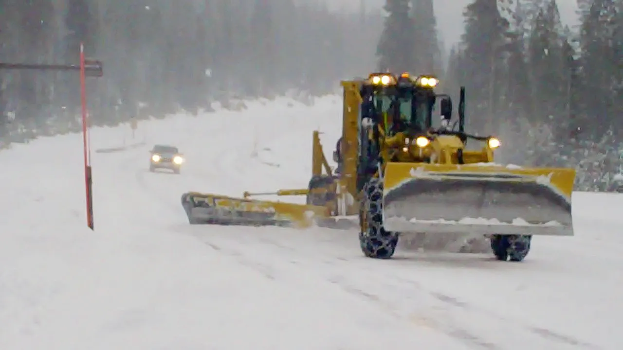 An ODOT grader with a wing plow clearing snow on Century Drive in the pines southwest of Bend