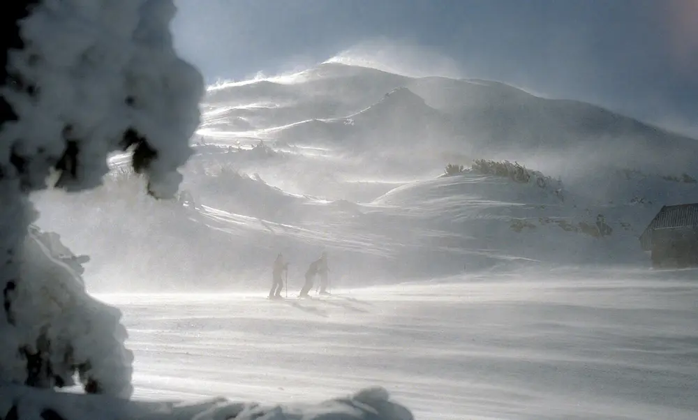 Skiers crossing wind-blown snow below the summit of Mt. Bachelor