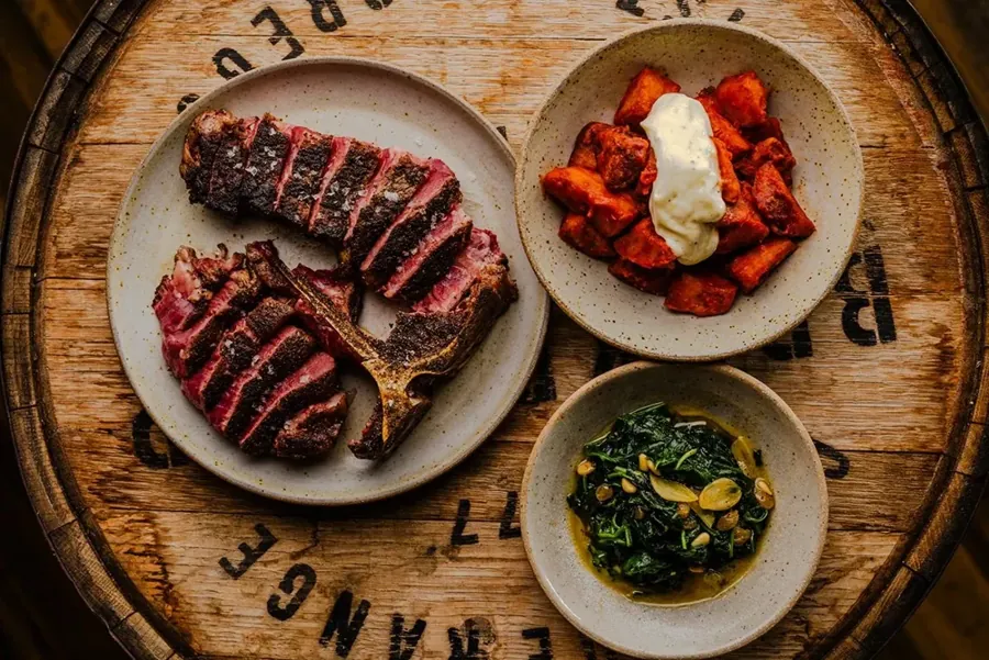 Sliced steak and small plates served on a barrel top from Rancher Butcher Chef in Bend