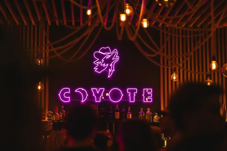 The pink neon COYOTE sign glowing behind the bar at the country bar in downtown Bend