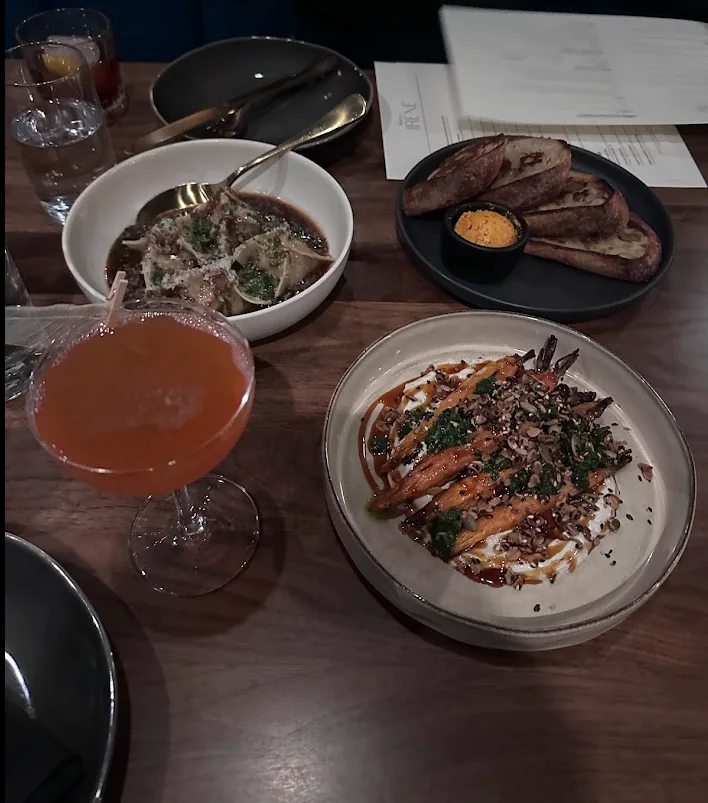 A cocktail with dumplings, roasted carrots and grilled bread on the table at Dear Irene in downtown Bend, Oregon