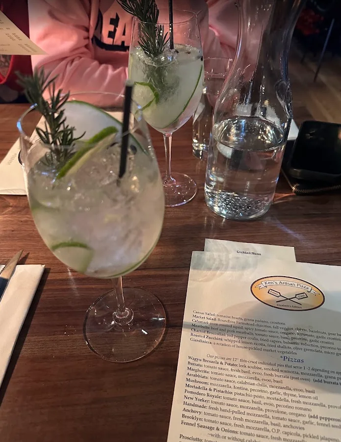 Two cocktails garnished with rosemary and cucumber next to the menu at Ken’s Artisan Pizza in downtown Bend, Oregon