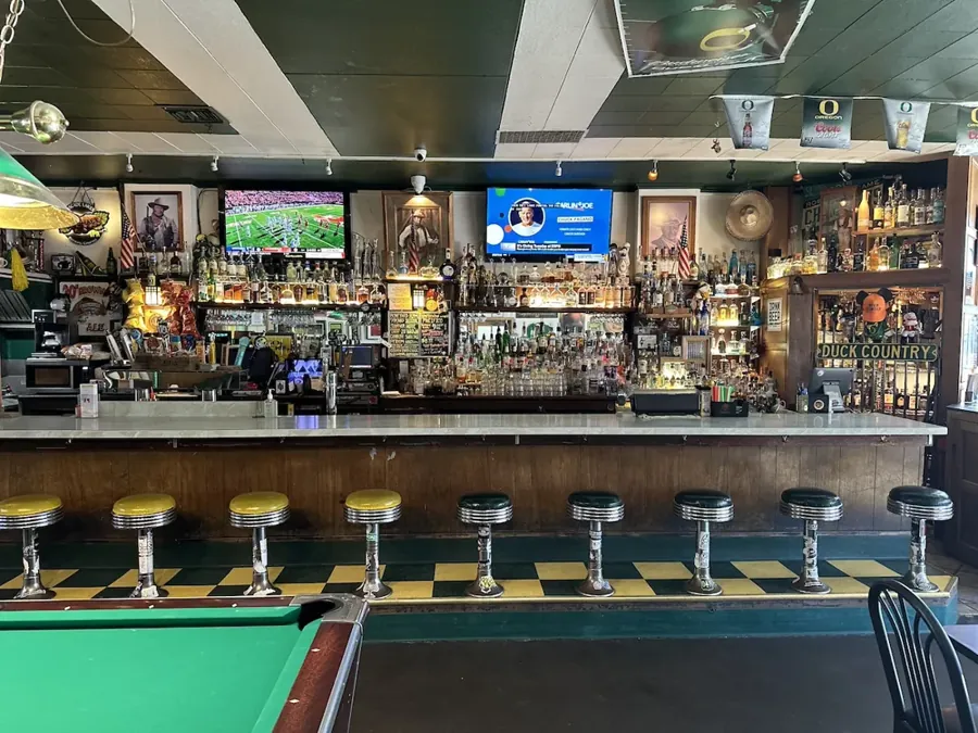 The long bar, stools and a pool table inside M & J Tavern in Bend