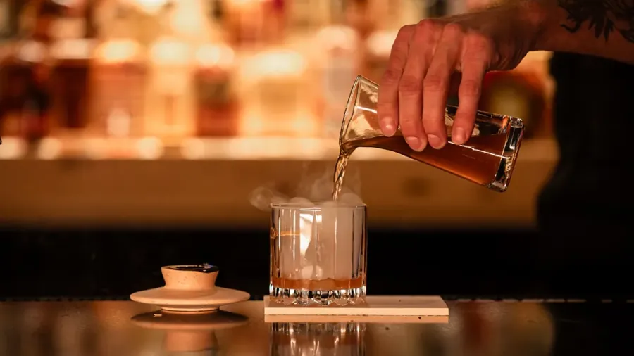 A drink being poured over ice at the bar at Roam in the Oxford Hotel, Bend