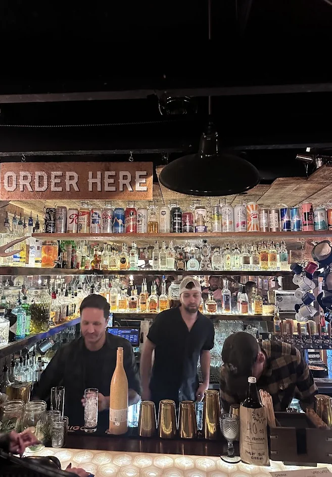 Bartenders working under the Order Here sign at Velvet, a small cocktail bar in downtown Bend, Oregon