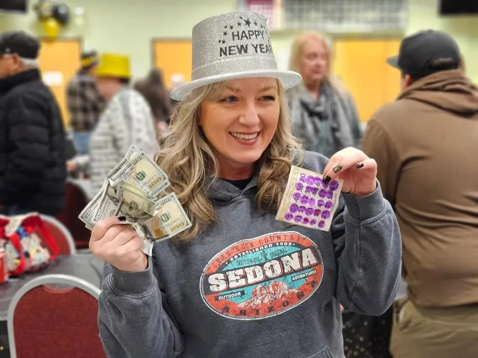 A smiling bingo winner holding cash at La Pine Senior Activity Center