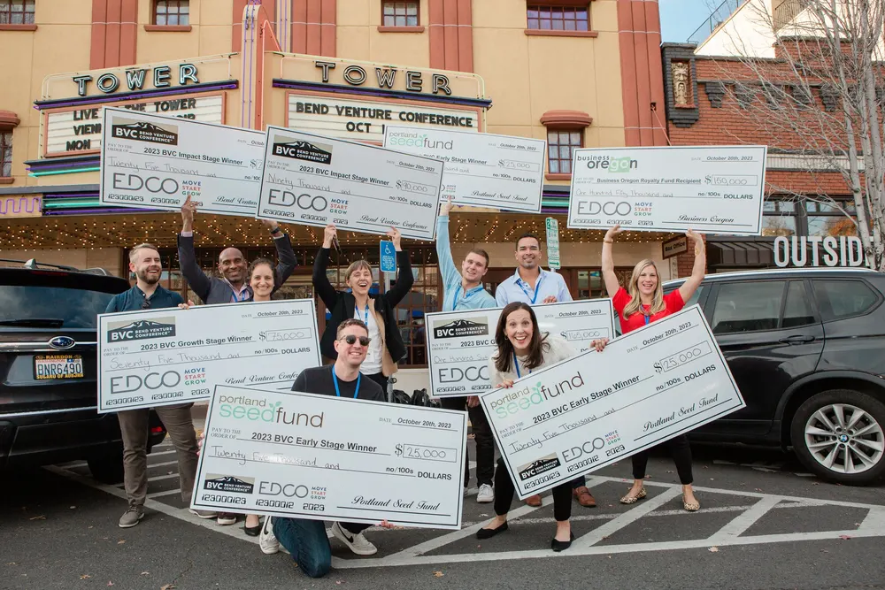 Bend Venture Conference winners holding oversized checks outside the Tower Theatre