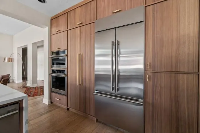A walnut cabinet wall with a built-in fridge by Bend Craftsmen Company