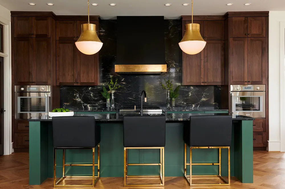 A green island with brass pendants and walnut cabinets in a Bend kitchen
