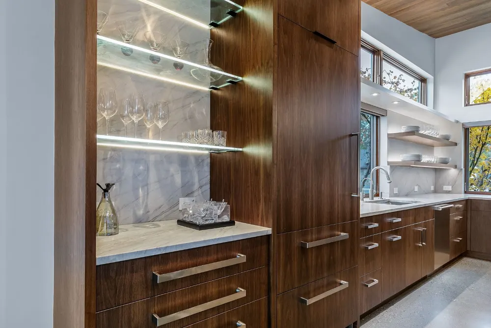 Walnut cabinetry with lit glass shelves by Deschutes River Cabinet & Closet