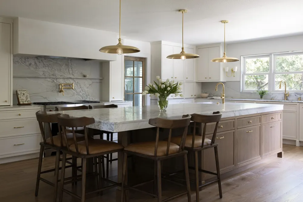 White kitchen with brass pendants and a big island by Woodworx by George