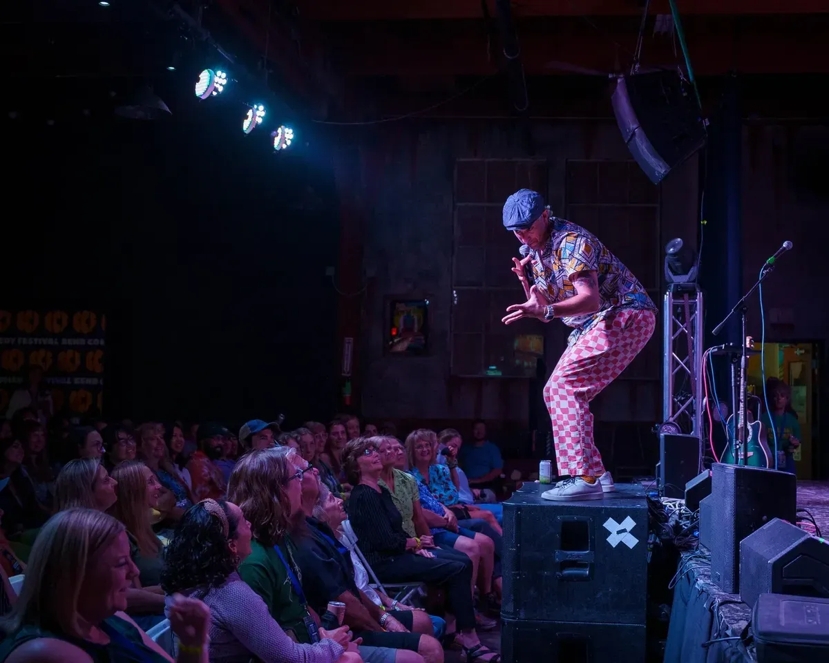 A comic on stage in front of a packed Bend Comedy Festival crowd