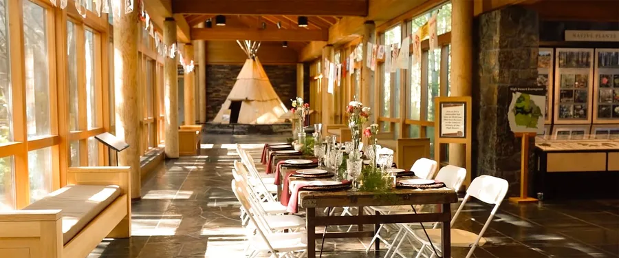 A long dinner table set in the sunlit glass hall at the High Desert Museum