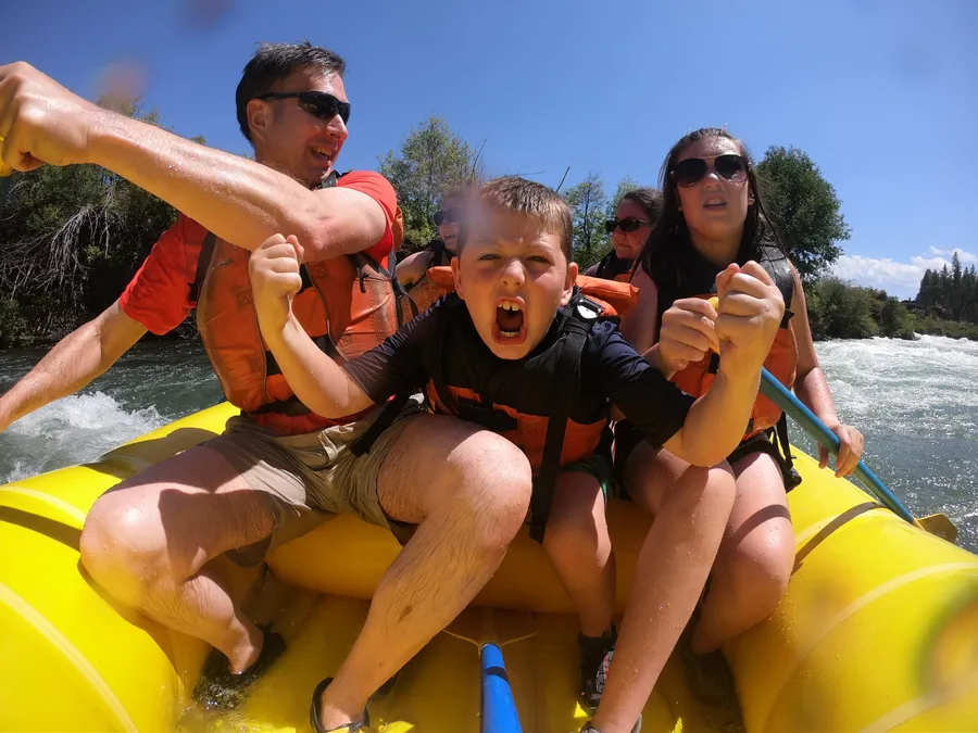 A group cheering in a raft with Seventh Mountain Rafting