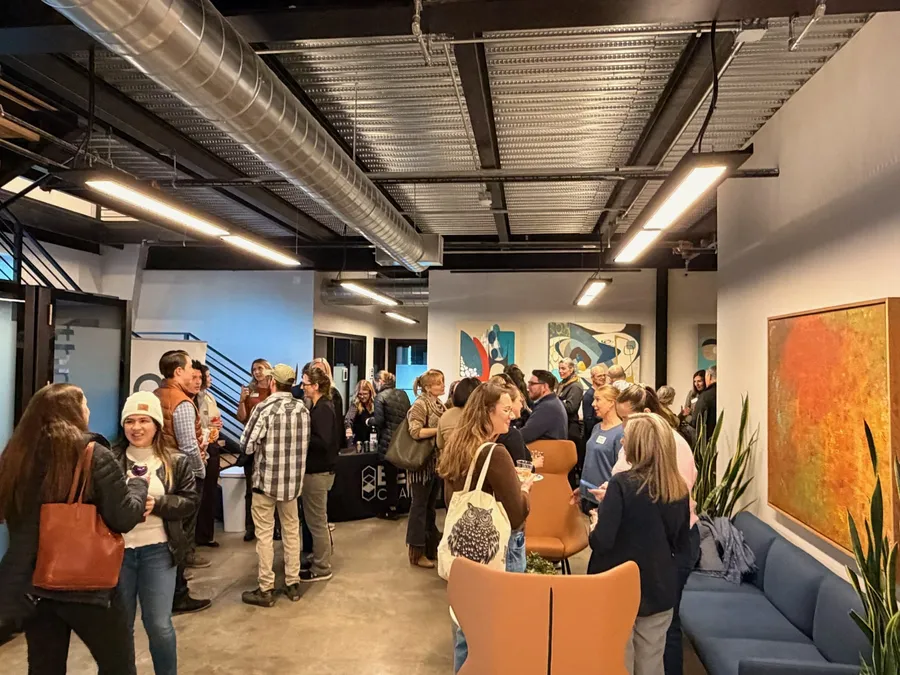 A crowd mingling at an evening event inside Work-Collective in Bend