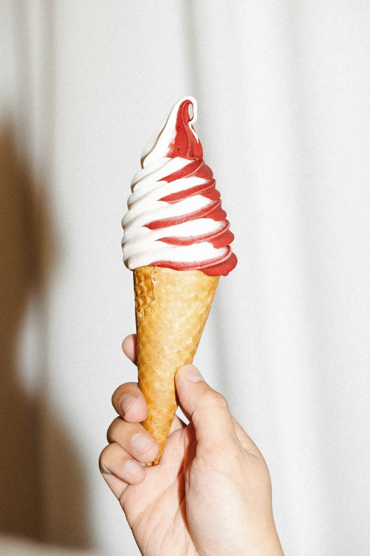 A hand holding a swirled real-fruit ice cream cone from Birdsong