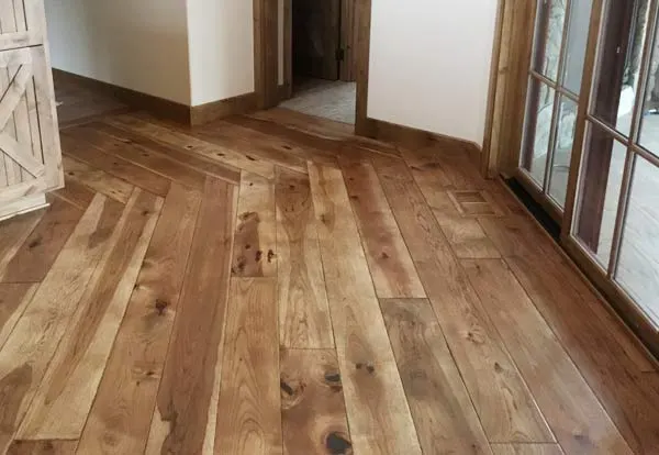 Wide-plank rustic hardwood floor installed through a bright room, from Exquisite Hardwood Floors