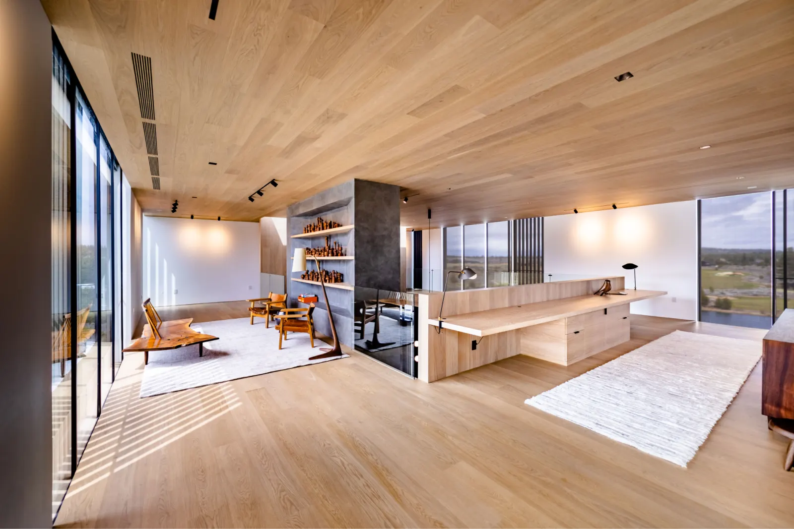 Open living room with pale wide-plank wood floors and floor-to-ceiling windows in a Tetherow home in Bend