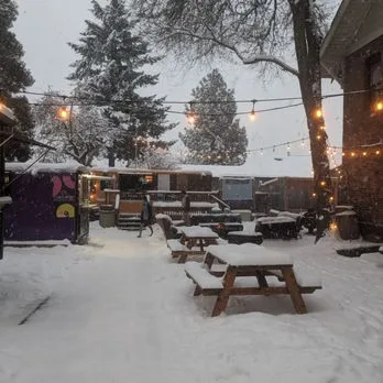Snow on the picnic tables and string lights in the beer garden at Bunk+Brew in Bend, Oregon