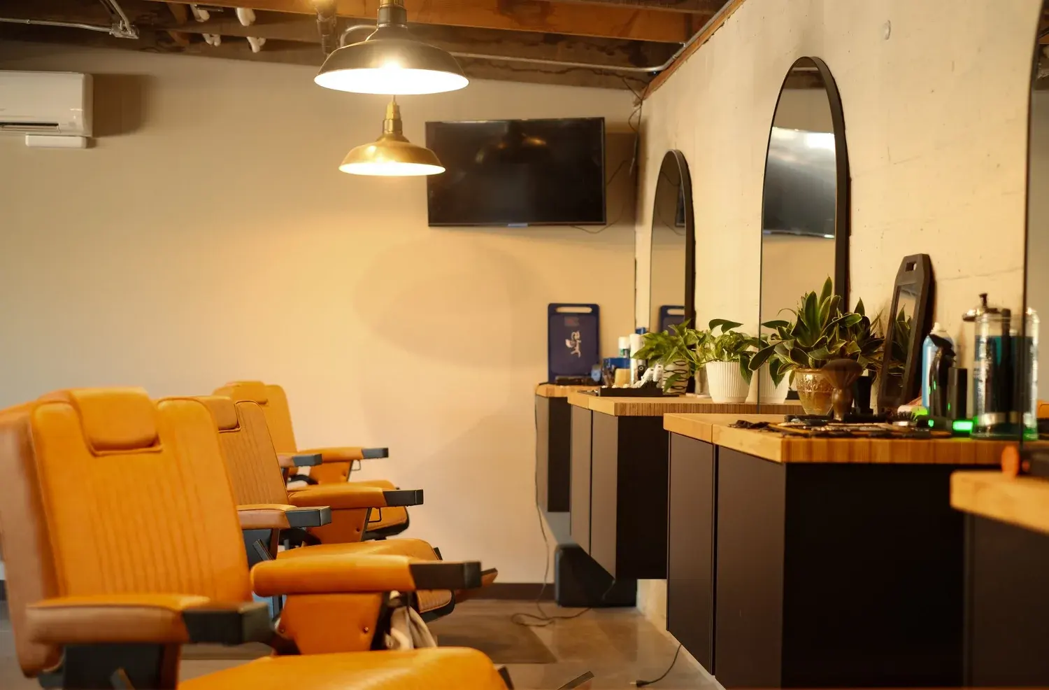 Tan leather barber chairs, arched mirrors and plants inside Clover Cuts Barbershop on NW Hill Street in Bend