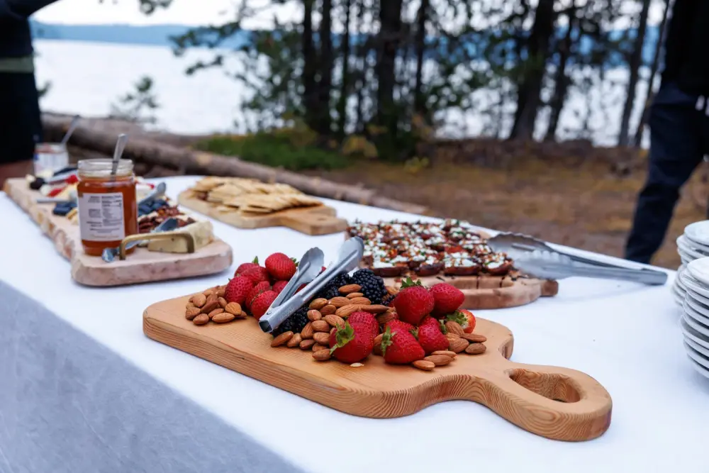 A lakeside grazing table with berries, almonds and boards set out under the pines at Paulina Lake