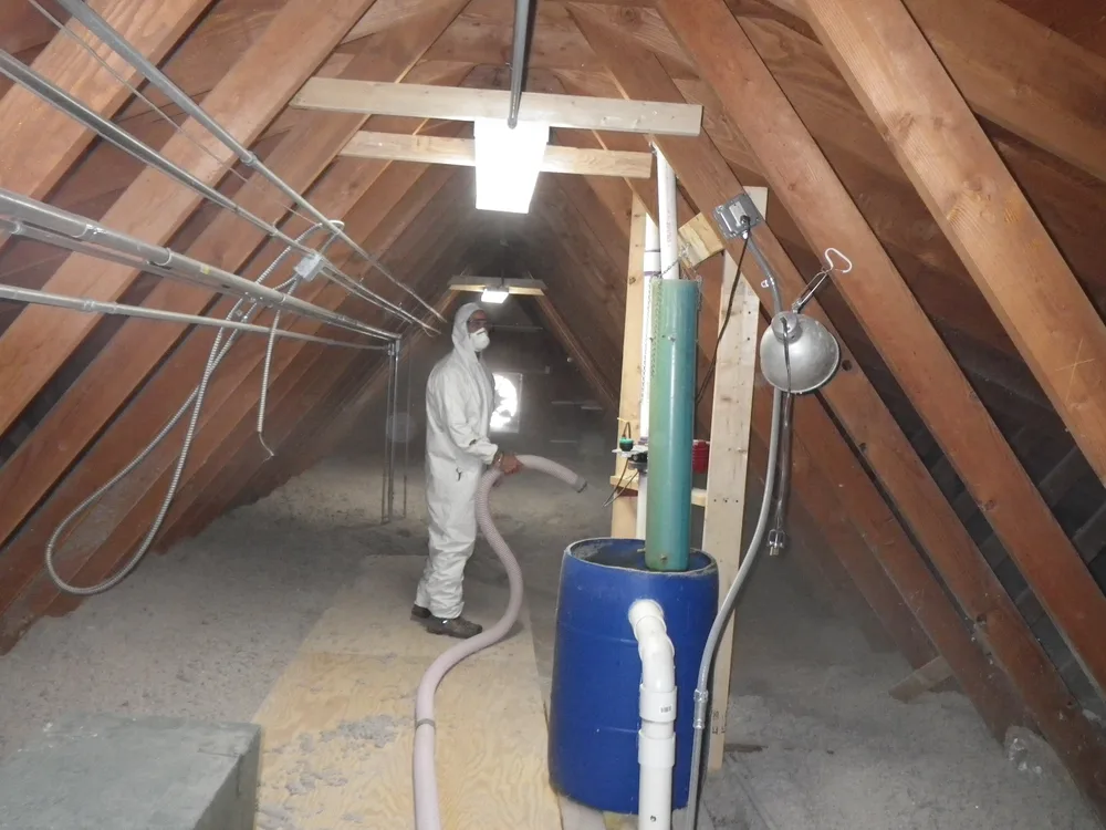 Worker blowing loose-fill insulation into an attic