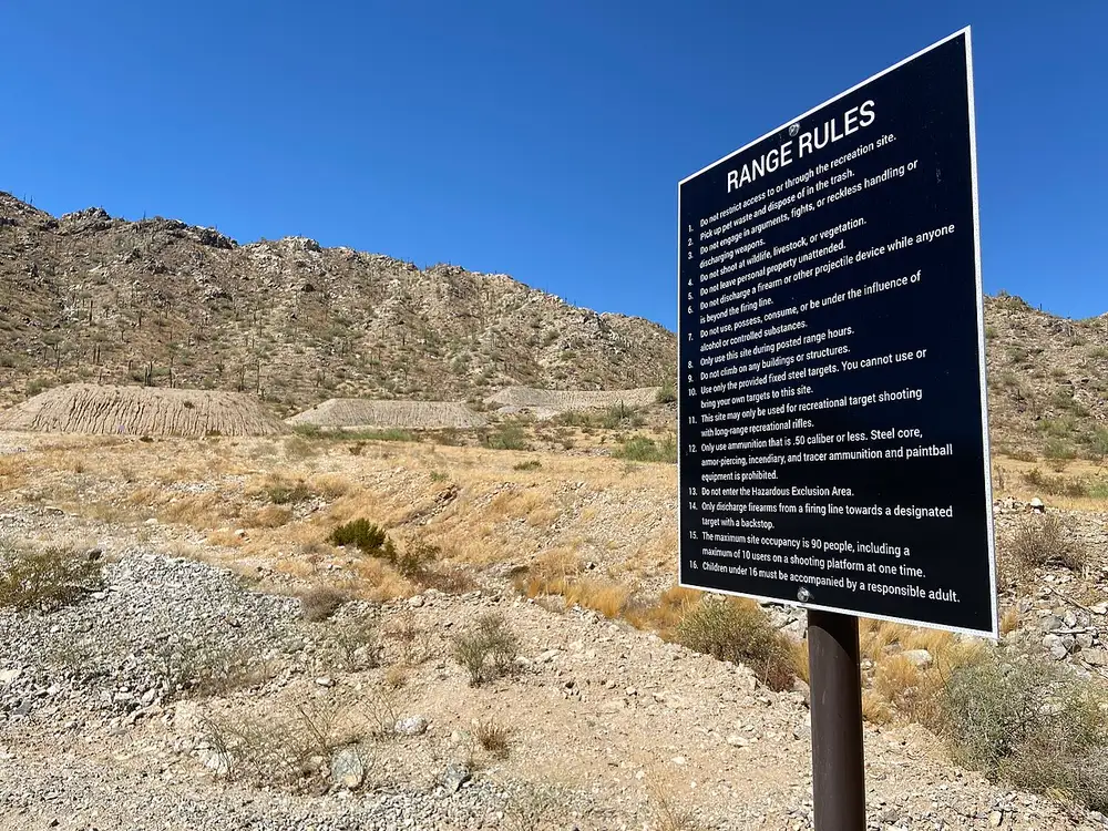 A Bureau of Land Management Range Rules sign posted beside a desert shooting site
