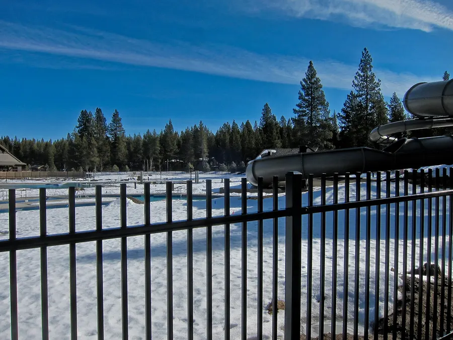 Snow-covered pools and water slides at the SHARC recreation center in Sunriver, ringed by ponderosa pines