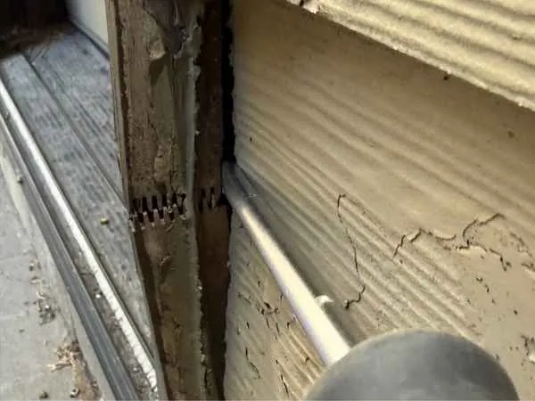 Decayed wood door trim at the base of a rear exterior door