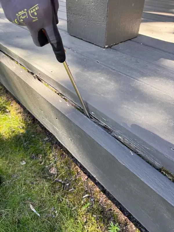 Inspector probing a soft deck rim board with a screwdriver