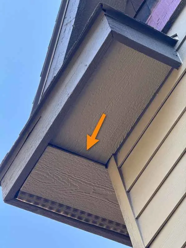 Soffit panel under an eave pulling away from its position