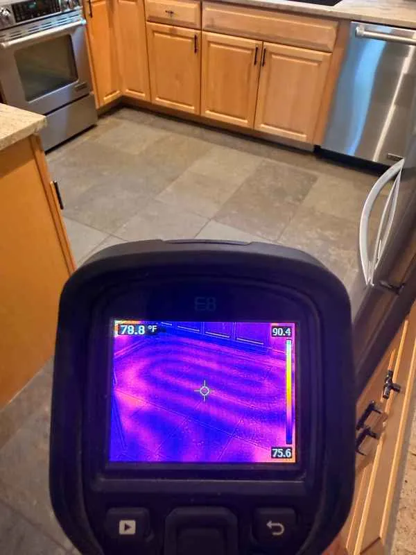 Thermal camera screen showing warm radiant floor tubing loops under a tile kitchen floor