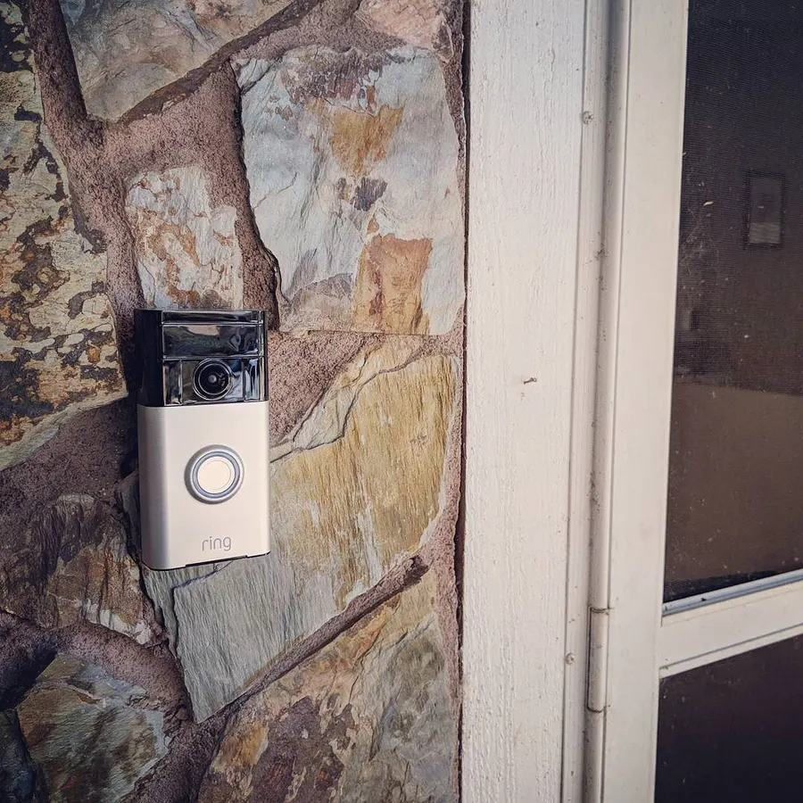 A video doorbell mounted on a stone wall beside a front door