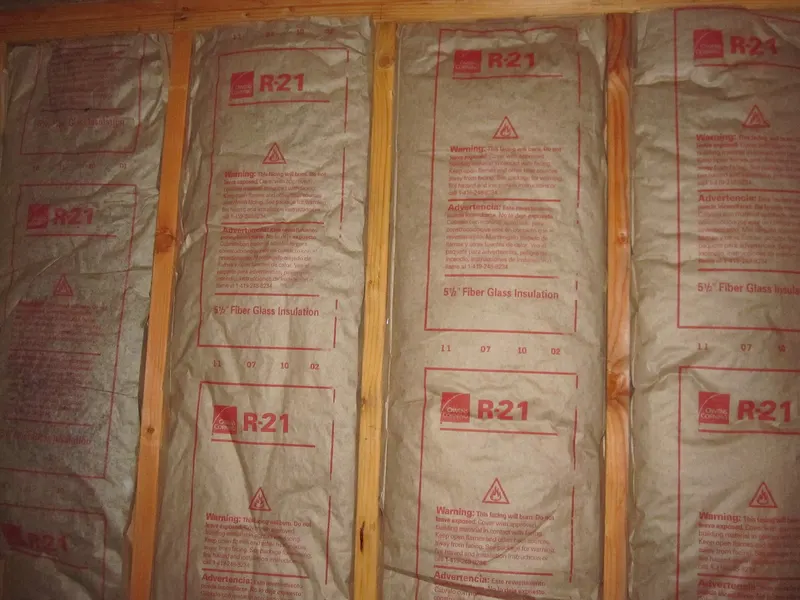 Kraft-faced fiberglass batts printed with R-21 stapled between wall studs