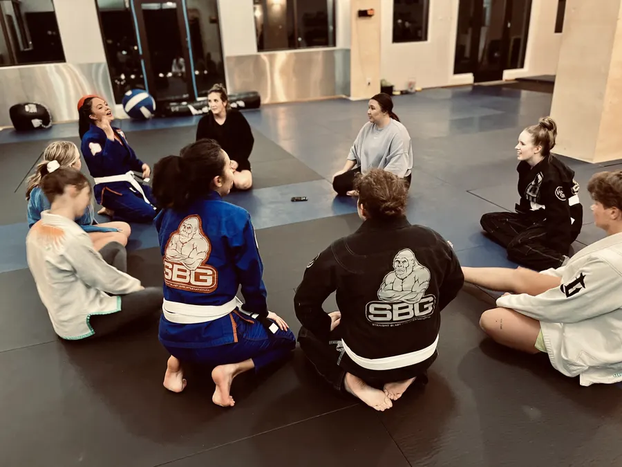 Women and teen girls in gis and sweats sitting in a circle on the mats at SBG Bend