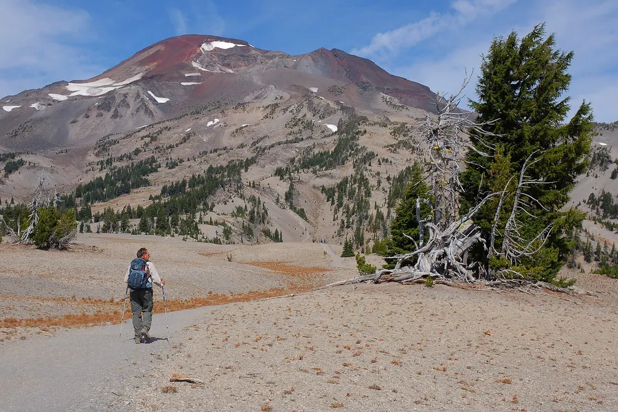 A hiker with a backpack walks a pumice trail toward South Sister in the Three Sisters Wilderness