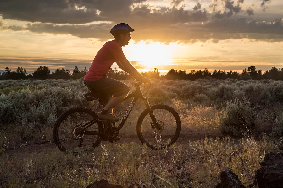 A mountain biker silhouetted against a golden sunset on a high-desert trail at Cline Buttes