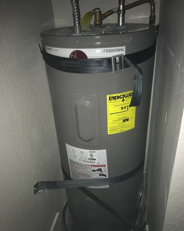 A gray Rheem 40-gallon electric water heater held to the wall with black seismic straps