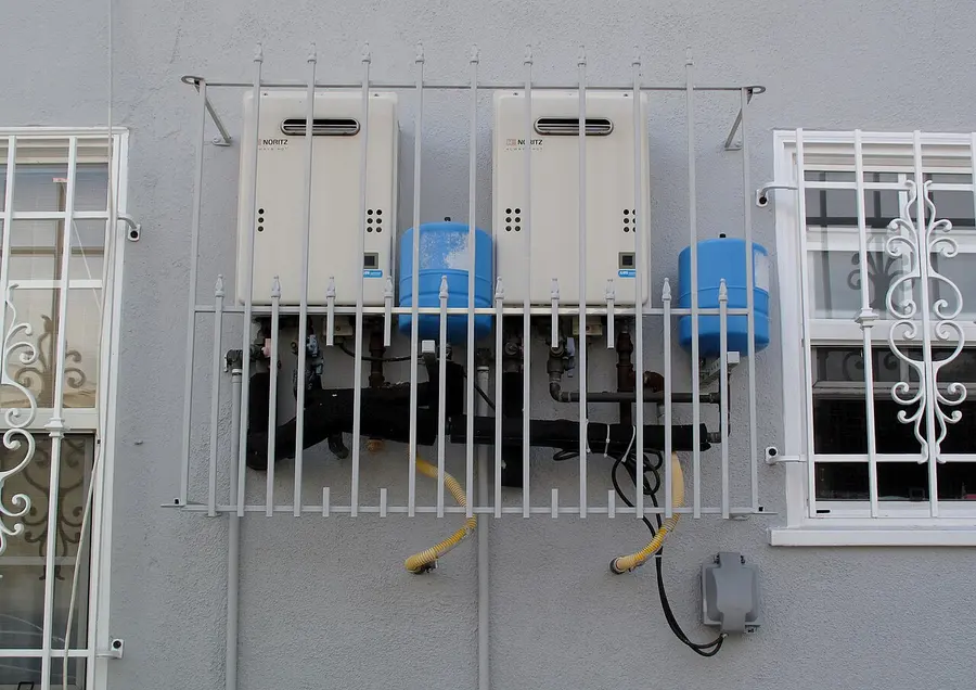 Two wall-mounted Noritz tankless water heaters with blue expansion tanks on an exterior wall