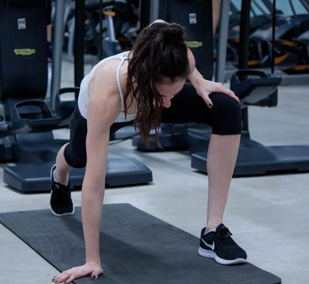 A woman stretching on a mat at Embark Fitness