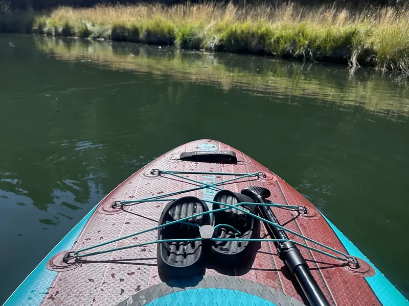 The front of a paddleboard on the calm Deschutes River