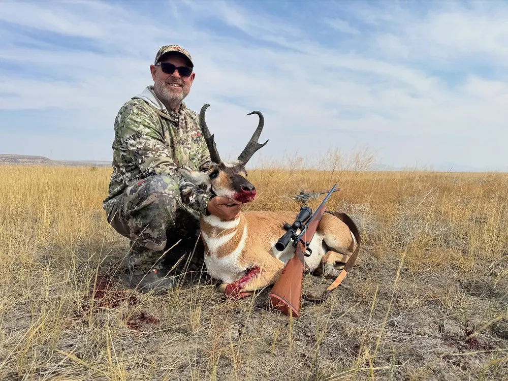 An AOA Outfitters hunter with a pronghorn buck in high desert grass
