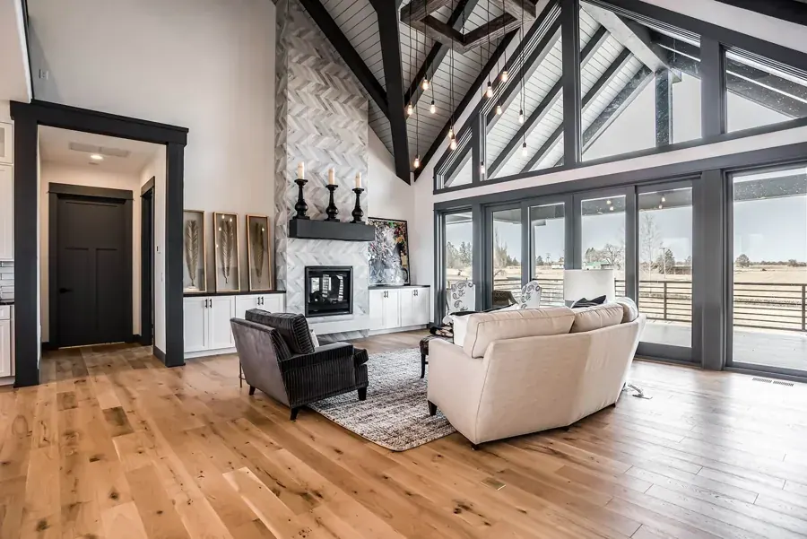 A great room with exposed trusses and a wall of glass doors by Complements Home in Bend