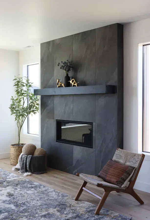 A dark tiled fireplace wall with a leather chair, finishes from Element Design Collective in Bend