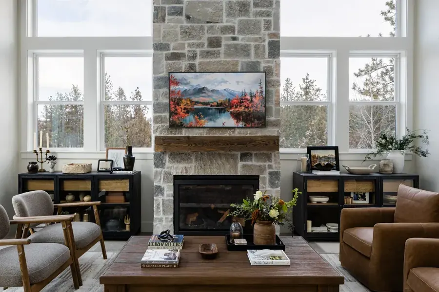 A living room with a stone fireplace and built-ins by Fishhouse Design Studio in Bend