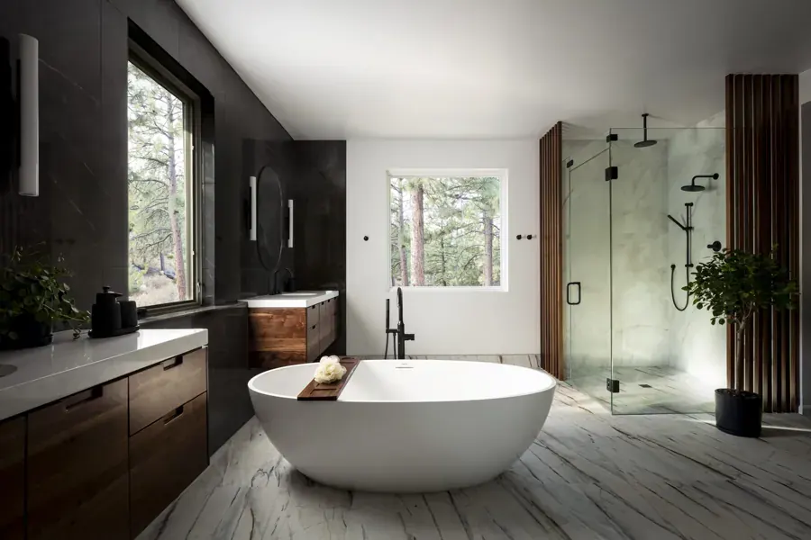 A bathroom with a freestanding tub and dark wood vanity by Iron Roots Design in Bend