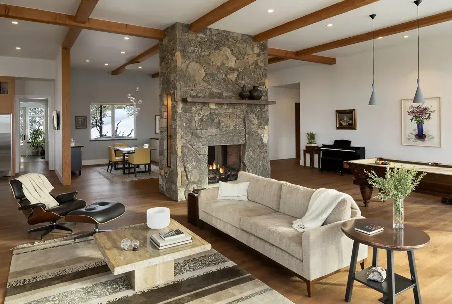 A great room with a stone fireplace and timber beams designed by Legum Design in Bend