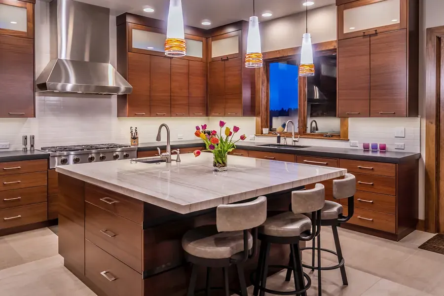 A kitchen with warm wood cabinets and glass pendants designed by Patty Jones Design in Bend