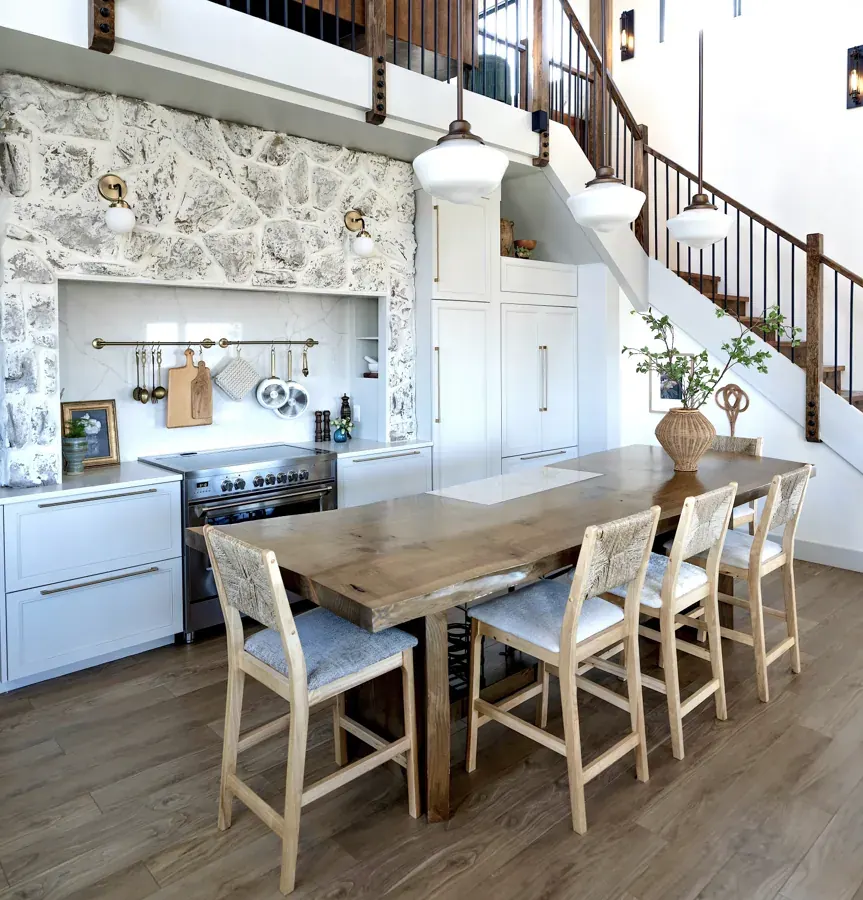A kitchen and dining room with a stone backsplash and stair by PJ Hurst Design in Bend
